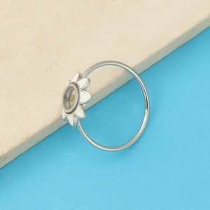 Detail of silver sunflower ring with white enamel petals and central mustard seed chamber