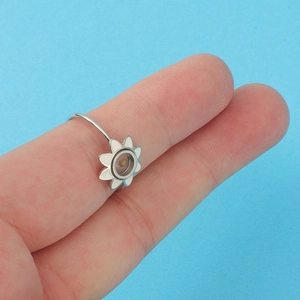 Silver stainless steel daisy ring for women worn on finger with vibrant blue background