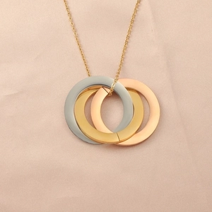 Macro shot of interlocking triple ring pendant in gold, silver, and rose gold finishes