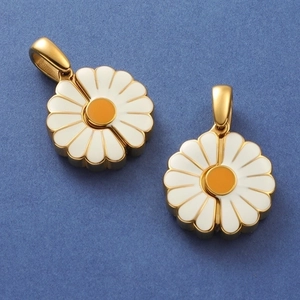 Macro view of gold daisy pendants with white enamel petals and yellow center detail