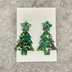 Close-up of glittery acrylic Christmas tree earrings with colorful sequins on white card