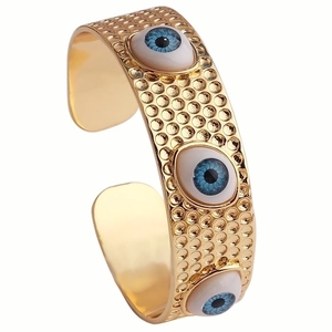 Bracelet jonc Evil Eye doré avec breloques en résine bleue et texture martelée