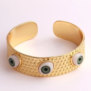 Vue macro d'un bracelet doré réglable avec finition texturée et charmes d'yeux maléfiques