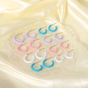 Pastel C-shaped stainless steel earrings in assorted macaron colors on glass tray
