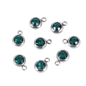 Macro detail of eight dark green round birthstone charms with silver stainless steel bases