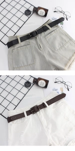 Détail de ceintures en cuir noir et marron sur un short en jean avec boucles en métal rétro