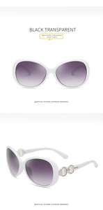 Detail of white sunglasses with purple gradient lenses and gold interlocking ring hinge