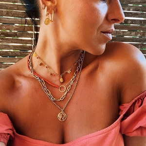 Detail of layered gold hip-hop chain necklace with coins, red beads, and earrings