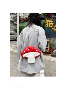 Outdoor shot of a creative red and white mushroom crossbody bag with chain strap