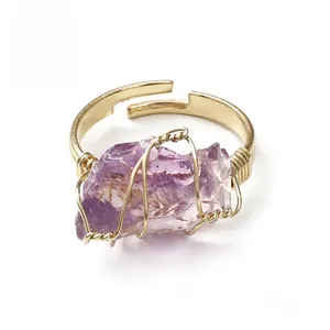 Detail of handmade wire-wrapped ring with irregular raw purple amethyst and gold band