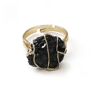 Detail of handmade gold wire-wrapped ring featuring a natural raw black gemstone