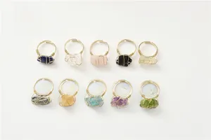 Top view of ten assorted natural raw stone rings with handmade gold wire wrapping