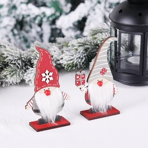 Pair of festive wooden Christmas gnome ornaments with red and grey hats on snowy background