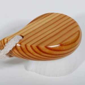 Detail of wooden facial brush with soft white bristles and a natural hemp hanging rope