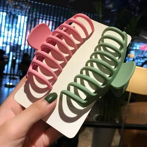 Matte pink and green large shark hair claws for women displayed in a warm setting