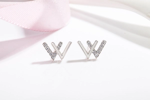 Macro shot of silver W-shaped earrings with sparkling cubic zirconia and polished finish