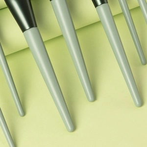 Detailed close-up of light green makeup brush handles with dark green metal ferrules