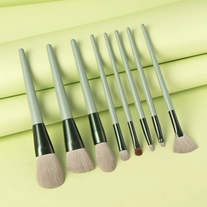Detailed set of 8 makeup brushes with light green handles on decorative background