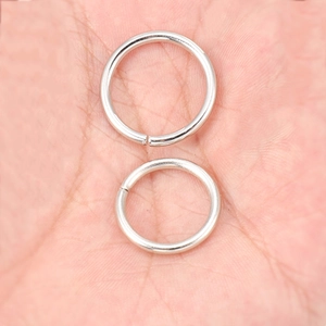 Silver metal jump rings for jewelry making shown in two sizes on a palm background