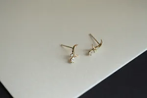 Detail of 14K gold plated silver crescent moon stud earrings with sparkling cubic zirconia