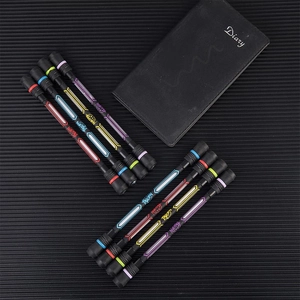 Diagonal array of balanced spinning pens in four colors on a textured black background