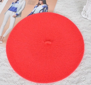 Flat lay of a red wool beret cap on white lace and magazine background with top view