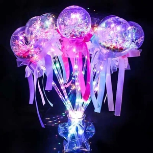 Close-up of glowing LED balloons with colorful confetti, ribbons and star glass bottles