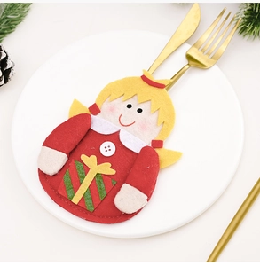 Close-up of a festive Christmas doll cutlery holder on a white plate with gold utensils