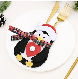 Close-up of a festive penguin cutlery holder in felt on a white plate for Christmas decor