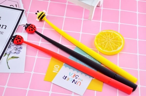 Detailed view of bee and ladybug silicone charms on clover leaf gel pens with ink