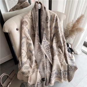 Detail of beige cashmere-feel scarf with paisley patterns and elegant fringe drapes