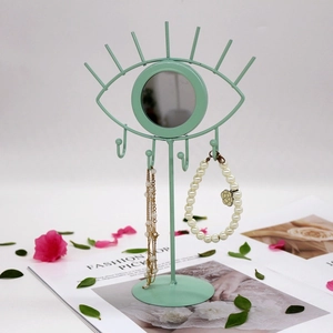 Pale green eye-shaped metal jewelry display rack with a center mirror and hanging hooks