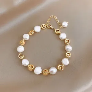 Detailed macro view of baroque pearl bracelet with gold carved beads on champagne satin