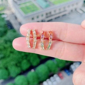 Detail of curved gold hoop earrings with white and rainbow cubic zirconia stones