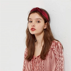 Detail view of a burgundy satin knotted headband worn by a model for an elegant look