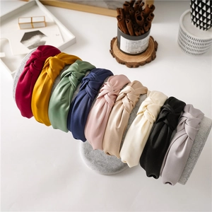 Detailed set of nine multi-colored satin knotted headbands displayed on a gray stand