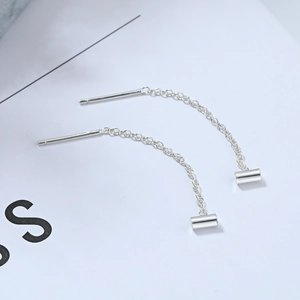 Detail of silver threader earrings featuring slender chains and minimalist cylindrical drops