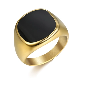 Détail de bague chevalière dorée avec insert noir lisse et finition en métal brossé