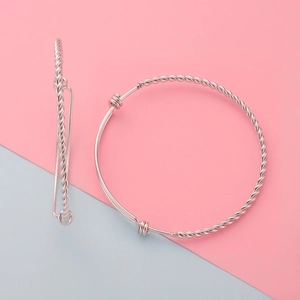 Close-up of adjustable stainless steel bangles with twisted rope texture on pink and blue background