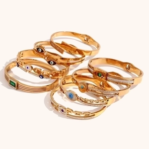 Dettaglio di bracciali placcati in oro 18K con motivi malocchio e pietre verdi