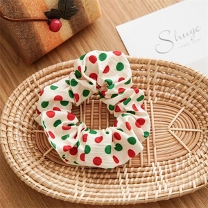 Detail of red and green polka dot bow scrunchie in a wicker basket on a wooden table