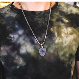 Detail of masonic shield pendant with G symbol and twisted chain on camouflage background