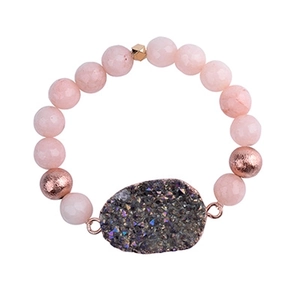 Macro detail of pink natural stone beaded bracelet with dark grey druzy geode pendant