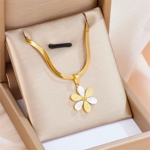 Gold snake chain necklace with white daisy pendant presented in a beige jewelry box