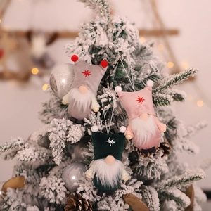 Christmas gnome ornaments set with festive hats on snowy tree branches in warm bokeh light