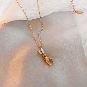 Detail of rose gold mechanical rabbit pendant with luck engraving on satin background