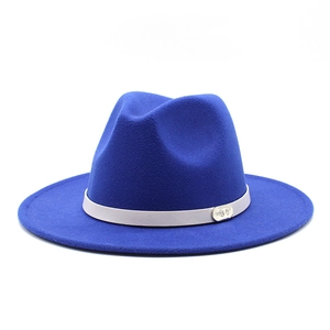 Close-up of royal blue wool fedora with a grey ribbon and silver logo plate detail