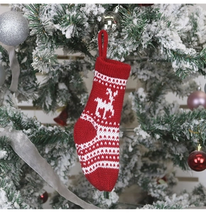 Détail d'une chaussette de Noël en tricot rouge avec motif renne sur un sapin festif