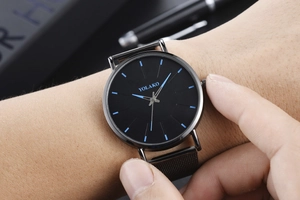 Close-up of YOLAKO quartz watch with black dial, blue markers and black mesh strap