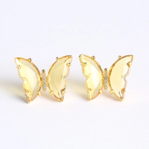Detailed close-up of yellow glass butterfly earrings with gold plating and zircon stones